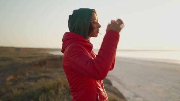 Portré gyönyörű ihletett nő túrázó nézi a tengerparton napkeltekor — Stock videók