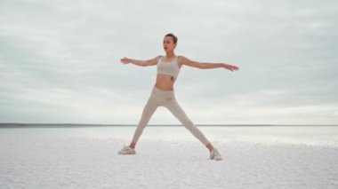 Uzun soluklu parallax çekimi. Güzel fitness kadını. Kuru tuz gölü kıyısında yoga pozisyonu alıyor.