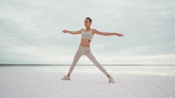 Parallax full length shooting young beautiful fitness woman practicing yoga postures on dry salt lake coast — Stock Video