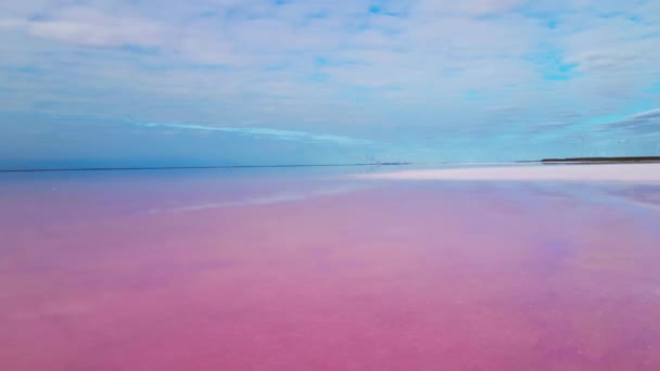 AERIAL, CERRAR: Volando cerca por encima de la superficie de agua lisa de increíbles lagos de color rosa de Sivash, Ucrania. Hermosas salinas rojas y violetas sobre fondo azul del cielo — Vídeo de stock