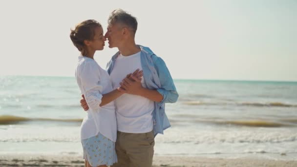 Στοργικό ζευγάρι αγκαλιάζει, κρατώντας τα χέρια, φιλιά και απολαμβάνοντας ηλιόλουστο πρωινό στις διακοπές στην παραλία — Αρχείο Βίντεο