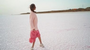 Büyük kazaklı, pembe elbiseli pembe elbiseli pembe göl manzaralı güzel tuz düzlüklü bir kız.