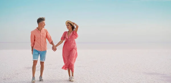 Tyylikäs tyylikäs pari kävelee valkoisella suolaisella rannikolla näyttää aavikolta, häämatka loma — kuvapankkivalokuva