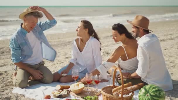 Loisirs, vacances d'été, manger, les gens au pique-nique et concept de nourriture - amis heureux prendre le petit déjeuner à la fête de plage d'été ou pique-nique. — Video