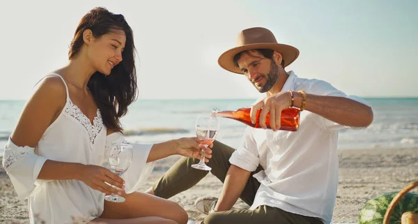 Romanttinen nuori pari juo viiniä ja nauttii piknikistä rannalla — kuvapankkivalokuva