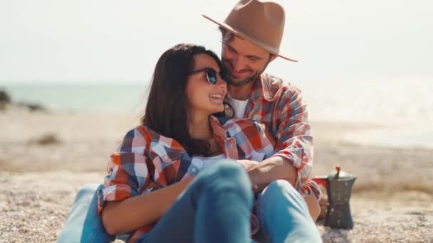 Felice coppia romantica si siede sulla spiaggia di mare, parla, ride e abbraccia — Video Stock