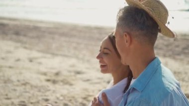 Deniz kıyısındaki neşeli bir çiftin yakın plan portresi. Bir adam kadının boynuna dokunuyor. Seyahat sırasında aşk anları.