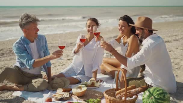 Gente animando con bebidas en la fiesta de picnic en la playa. Manos de la gente levantando tostadas con copas de vino, disfrutando de picnic al aire libre en la naturaleza en la playa — Vídeo de stock