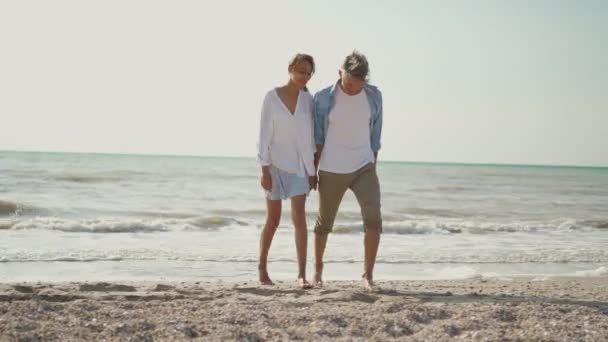 Freudig schön paar mit spaß laufen entlang sandstrand zusammen — Stockvideo