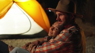 Karanlıkta plaj partisinde şenlik ateşinin önünde kadına sarılan adam..