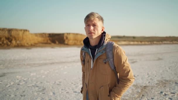 Portrait confident man walking at white salty flats and steep clay shore, slow motion — Stock Video