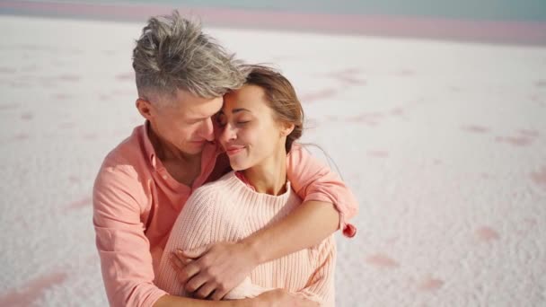 Camera lifting along man and woman hugging and tenderly touching each other on white desert or beach — Stock Video