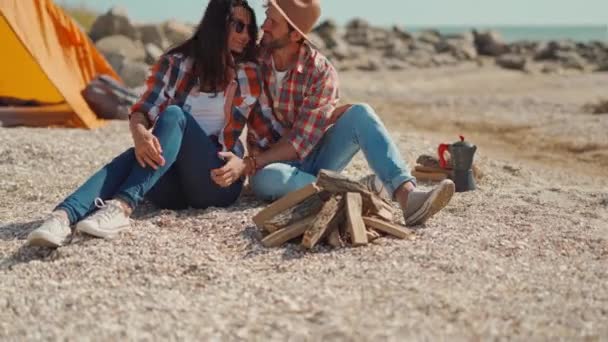Beautyful lovely couple sitting at campfire place on beach in seaside camping. — Stock Video
