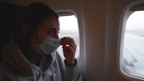 Mujer se sienta en la ventana del avión y usa máscara de seguridad médica en la cabina del avión. — Vídeo de stock