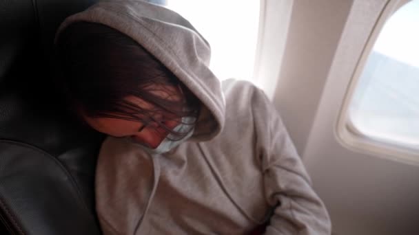 Penumpang wanita lelah dengan topeng wajah keselamatan nyaman tidur di kursi di jendela pesawat — Stok Video