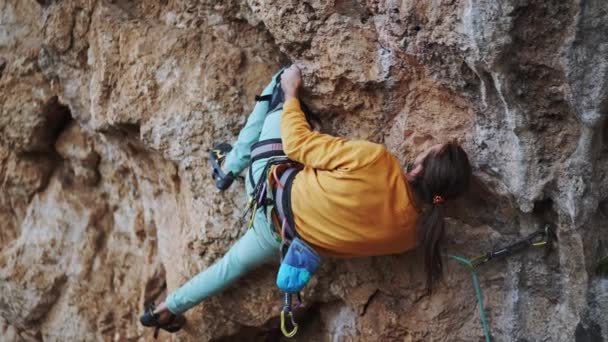 善于运动的男性攀岩者爬上悬崖峭壁。男人用腿固定墙壁，在困难的工作和动作前休息 — 图库视频影像
