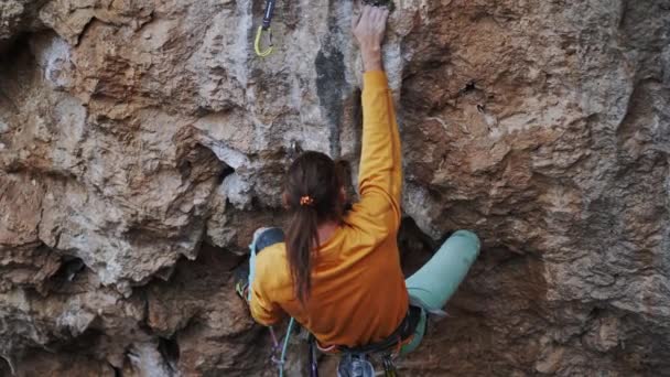 Close up top view Strong man climber climbs on tough high rock route outdoors, making hard wide move and clip rope. — Stock video