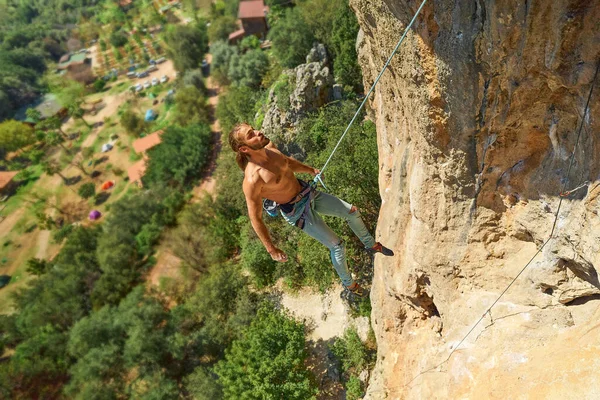 Starker muskulöser Mann Felskletterer hängt am Seil vor dem Fels, erkundet Route auf Klippe — Stockfoto