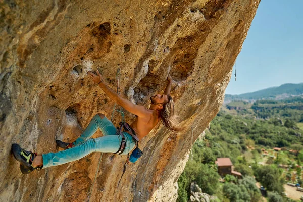 Urheilu vahva mies kalliokiipeilijä kiipeily Crag, katsot ylös, tarttuva ote — kuvapankkivalokuva