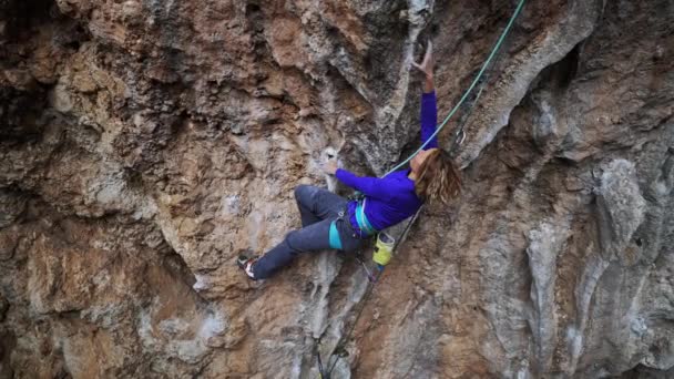 Chica fuerte escalador de roca sube toba de roca en el peñasco colgante. — Vídeo de stock