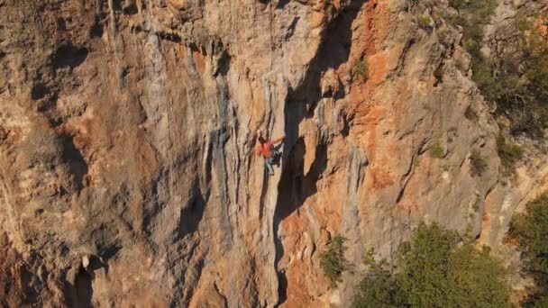 Luftaufnahme von der Drohne eines kräftigen, muskulösen Mannes klettert auf großen Tuffstein auf anspruchsvoller Kletterroute. — Stockvideo