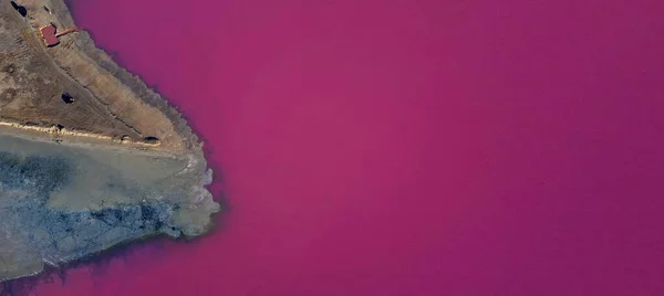 Letecký pohled shora na jasně růžové jezero vody s kusem země — Stock fotografie
