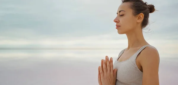 Крупним планом заспокоїлася жінка, що практикує йогу та медитацію на відкритому повітрі з видом на небо та озеро — стокове фото
