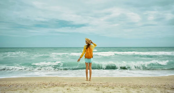 Vista al mar con olas y cielo nublado, mujer de pie en la playa en ropa de verano — Foto de Stock