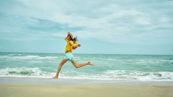 Juokseva onnellinen nainen hiekkarannalla, nauttien merimaisemista, vapauden tunteesta. — kuvapankkivalokuva