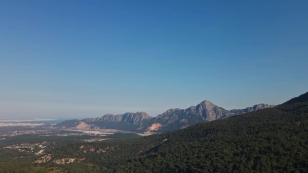 Vue aérienne depuis un drone survolant des bois sauvages sous une grande montagne. belle vue panoramique avec ciel bleu sur Antalya et crête de montagne rocheuse — Video