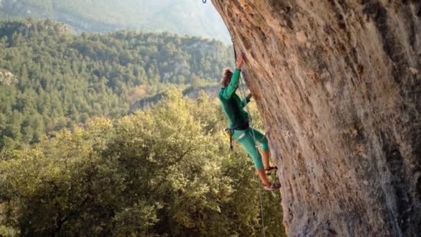 Güçlü ve güçlü kadın kaya tırmanışçısı, Türkiye 'nin güzel doğal arka planında uçurumun tepesinde sert kaya rotasına tırmanıyor. — Stok video