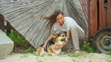 Neşeli kız gülüyor ve dışarıda sevimli Corgi köpeğiyle vakit geçiriyor.