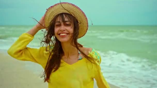ビーチで楽しさと楽しく走る黄色のシャツを着て髪を吹いて肖像幸せな表情の女性 — ストック動画