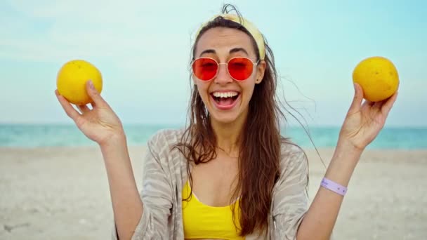 Divertida joven juguetona con ropa de verano sosteniendo frutas sobre sus ojos — Vídeos de Stock