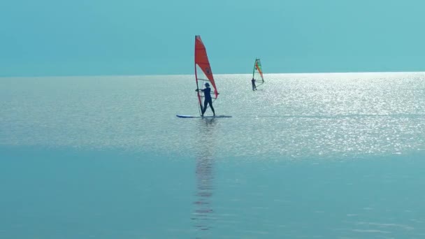 Силует віндсерфінгу, що пливе на дошці віндсерфінгу на морі на красивому небі заходу сонця на фоні. Здорові активні lfestyle, хобі, літні веселі пригоди . — стокове відео