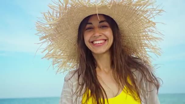 Close-up face smiling woman wearing straw hat at beach in sunshine sunrise on seashore. — Stock Video