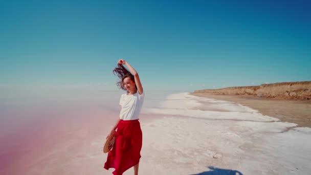 Slow motion beeldmateriaal mooi landschap en vrouw wandelen op wit strand in de buurt van zout roze meer — Stockvideo