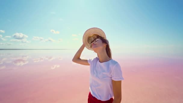 Mujer viajero en falda roja feliz en el lago de sal rosa brillante con cielo azul claro — Vídeo de stock