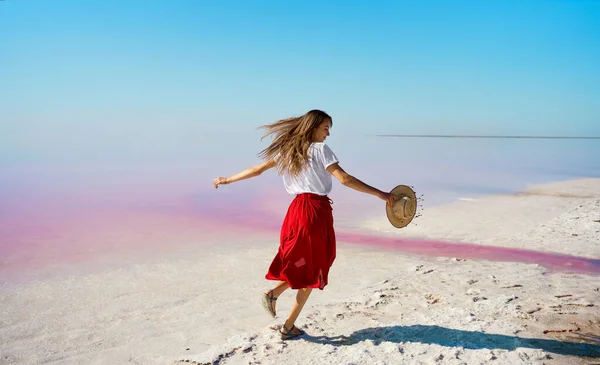 Iloinen nainen kulkee suola valkoinen ranta ja nauttia kesän matkustaa vaaleanpunainen järvi — kuvapankkivalokuva