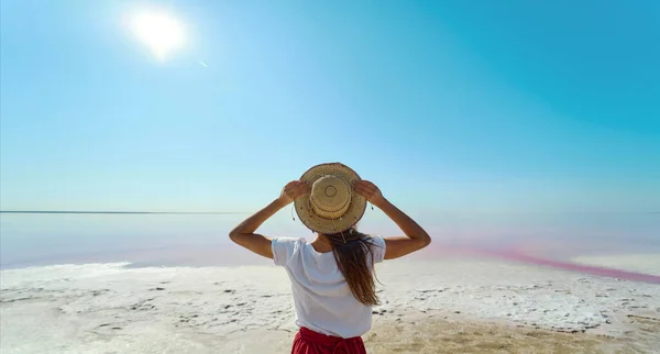 En kvinne i stråhatt som nyter vakker natur ved rosa saltsjø – stockfoto