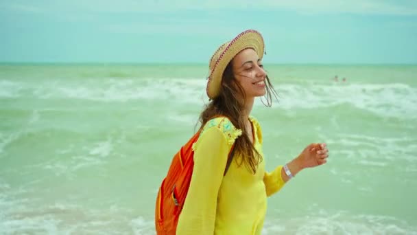 Authenticiteit portret gelukkig jonge vrouw met strohoed dragen geel shirt plezier hebben en het gevoel geluk tijdens het wandelen op het strand — Stockvideo