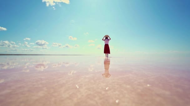 Vista trasera mujer en sombrero de paja disfrutando de la hermosa naturaleza en el lago de sal rosa — Vídeo de stock