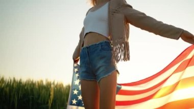 Genç, mutlu bir kadın altın gün batımında bayrak sallıyor.