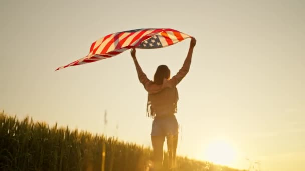 独立日，后视镜女子在战场上，日落时举着美国国旗 — 图库视频影像