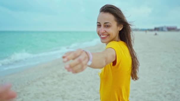 Portrét šťastný žena s foukající vlasy baví na pláži, drží někoho ruku — Stock video