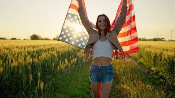 Amerykańska kobieta z dumą trzyma amerykańską flagę o zachodzie słońca, świętuje 4 lipca — Wideo stockowe
