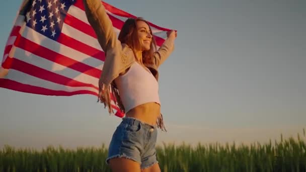 4 июля. Четвертое июля. Американская женщина с национальным американским флагом против красивой достопримечательности на закате — стоковое видео