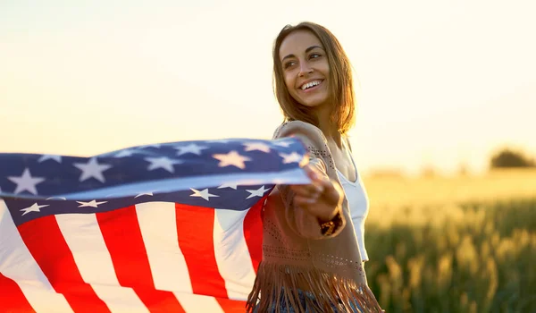 Donna patriottica americana che sventola stelle e strisce Bandiera USA al tramonto campo di grano — Foto Stock