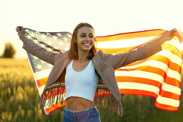 Donna americana con orgoglio regge bandiera americana al campo al tramonto, celebrare il 4 luglio — Foto Stock