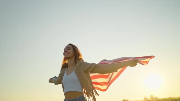 Nastolatka dziewczyna dumnie trzyma amerykański sztandar na polu ze złotym słońcem — Wideo stockowe
